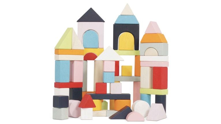 A large castle structure built from various geometric wooden blocks in muted pastel colors.