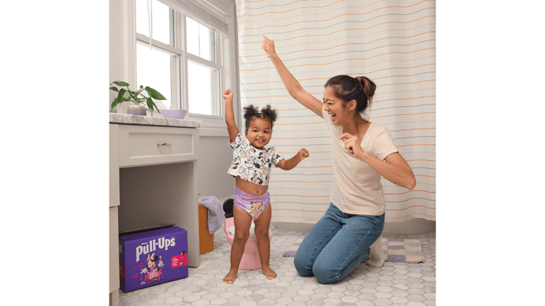 A mom and toddler daughter celebrate a potty training milestone in the bathroom.