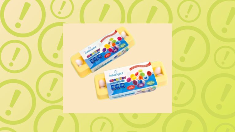 Two yellow plastic egg cartons containing toy matching eggs are shown wrapped in colorful product packaging labeled "The KiddoSpace Geometry Montessori Egg." The cartons are centered inside a pale cream square box, overlaid on a lime green background with a repeating pattern of faded exclamation marks inside circles.