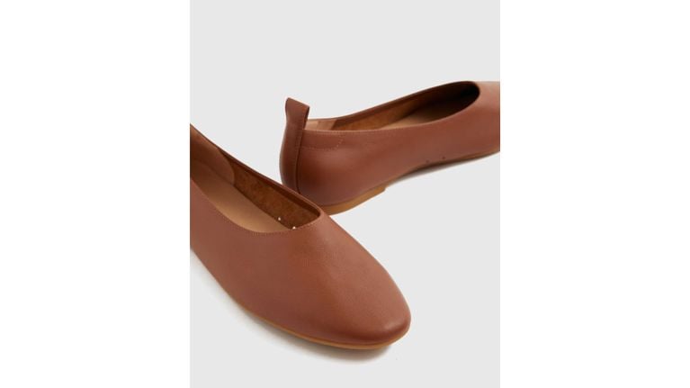 Close-up of a pair of cognac brown leather ballet flats with a square toe and pull tab.