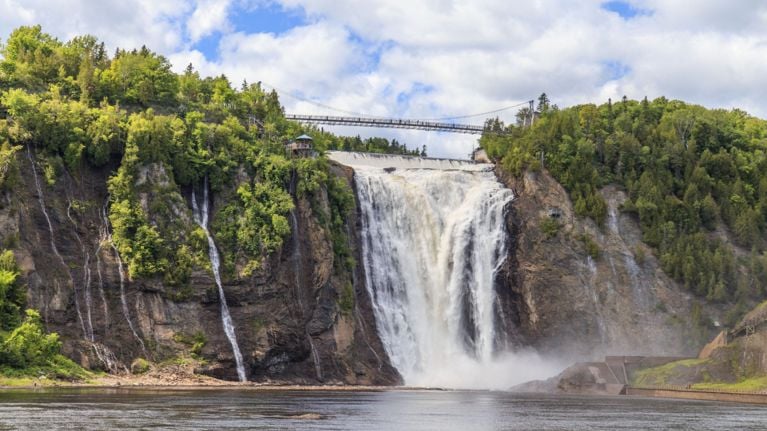 Montmorency Falls cascading down a rocky cliff, with a suspension bridge stretching across the top.