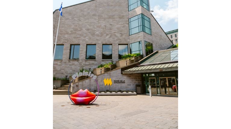 Entrance to the Musée de la civilisation in Quebec City, with a bright red lips sculpture in the plaza outside.