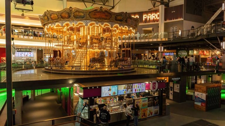 Indoor entertainment complex with a glowing vintage carousel at the centre, surrounded by food counters and walkways.