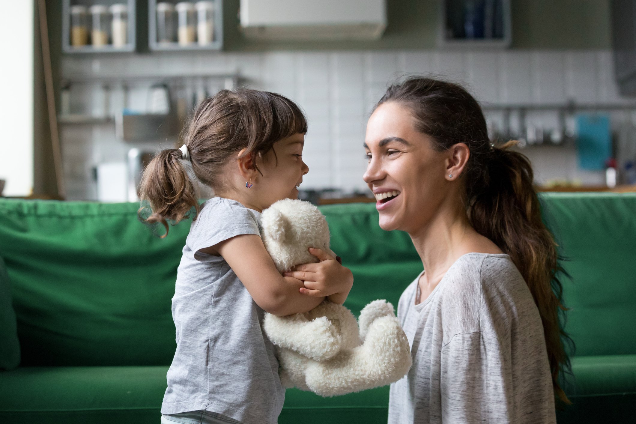 Smiling young loving mum talking with little preschool daughter with favorite stuffed toy
