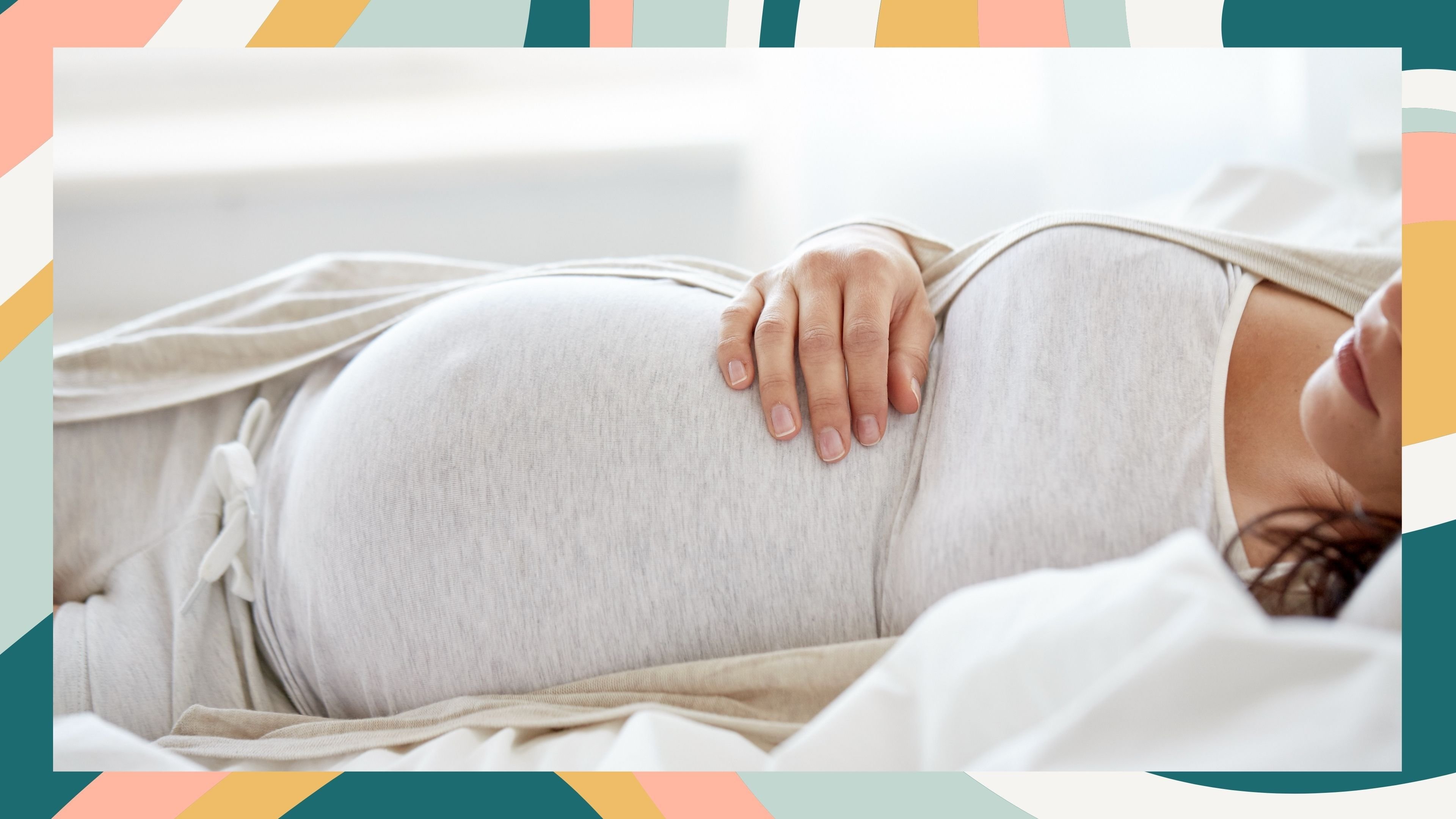 A pregnant person reclines on a bed in soft loungewear, one hand resting on their belly—surrounded by calming light and a colorful striped frame.