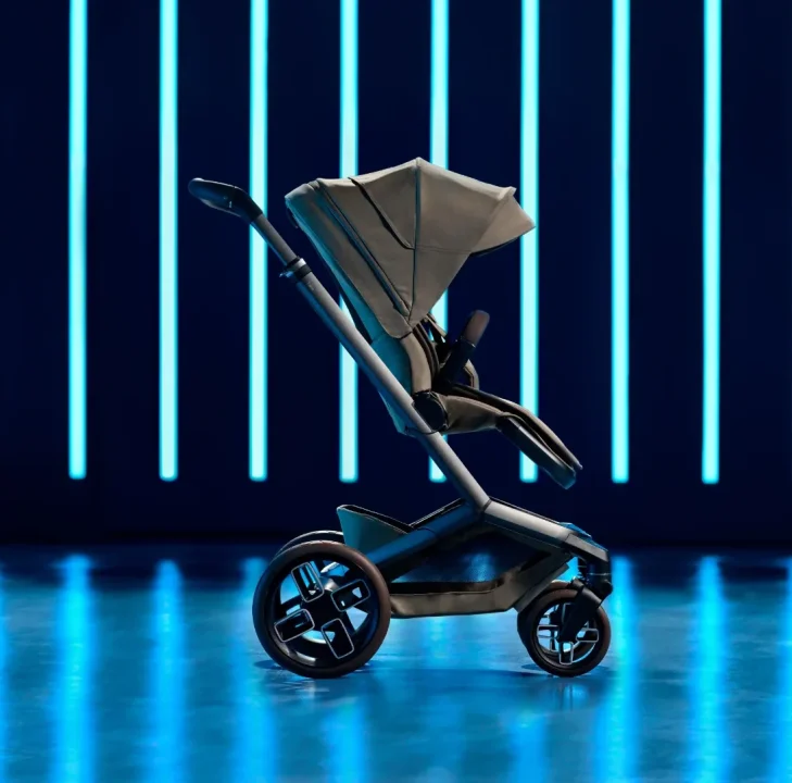 The Maxi-Cosi Fame stroller in a neutral taupe tone is shown in profile under dramatic blue lighting, highlighting its sleek frame, large wheels, and modern silhouette.